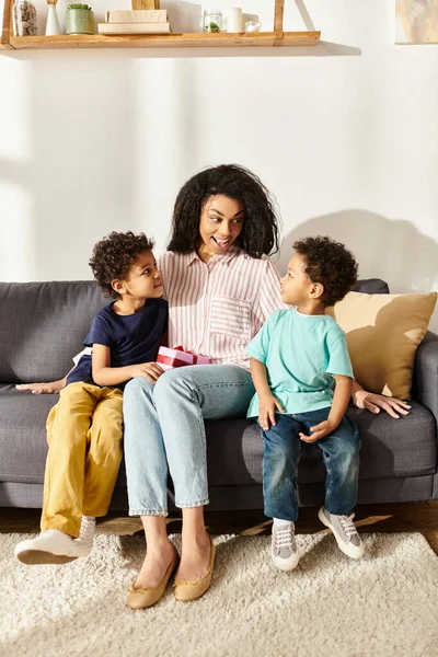 Радостная красивая африканская американка в домашней одежде проводит время со своими маленькими сыновьями, День матери — стоковое фото