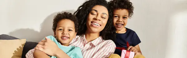 Jolly donna afro-americana sorridente alla macchina fotografica con i suoi piccoli figli carini, Festa della mamma, banner — Foto stock