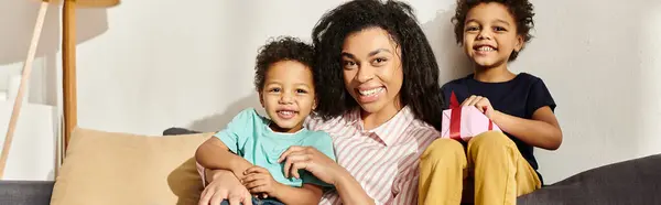 Gioiosa famiglia afroamericana di tre sorridenti alla macchina fotografica, presente in mano, Festa della mamma, striscione — Foto stock