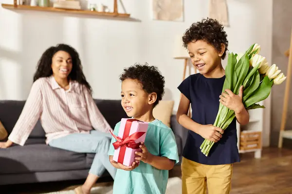 Concentrarsi su jolly bambini afro-americani con tulipani e presenti con la loro madre offuscata sullo sfondo — Foto stock