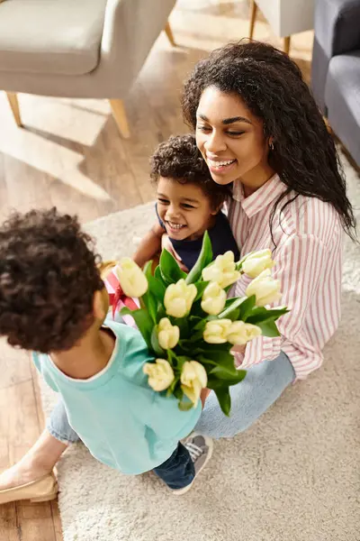 Femme afro-américaine joyeux recevant bouquet de fleurs fraîches de ses petits fils, Fête des mères — Photo de stock