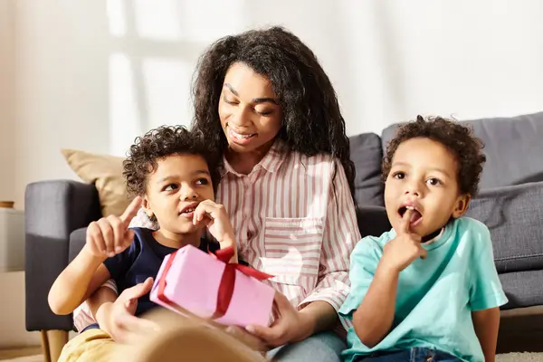 Familia afroamericana alegre de tres posando juntos y sosteniendo presente, Día de las Madres - foto de stock