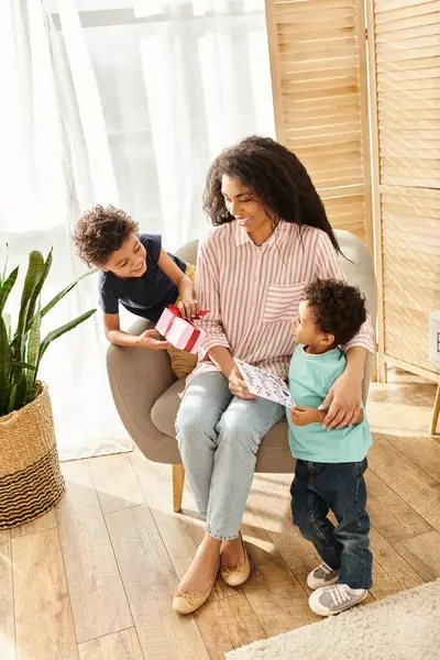 Feliz atraente mulher afro-americana recebendo cartão postal e presente de seus filhos, Dia das Mães — Fotografia de Stock