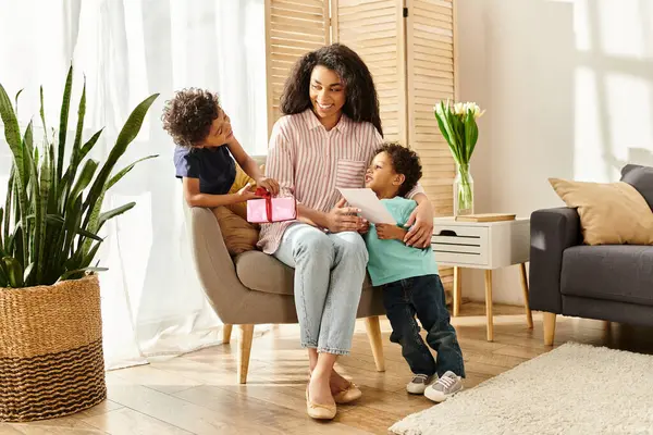 Jolly african american woman receiving gift and postcard from her adorable sons, Mothers day — Stock Photo