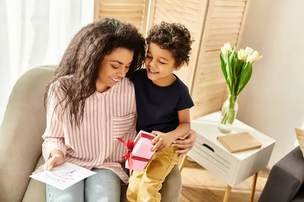 Joyful beautiful african american woman receiving postcard and gift from her son, Mothers day — Stock Photo
