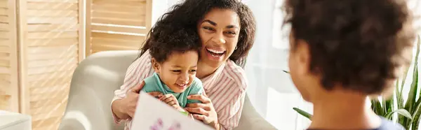 Merry african american woman receiving postcard from son with his brother, Mothers day, banner — Stock Photo