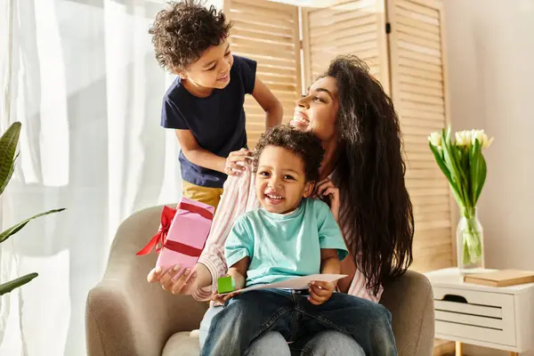 Jolly african american woman having great time with her kids, present and postcard, Mothers day — Stock Photo