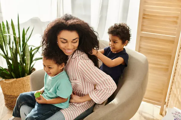 Adorable enfant afro-américain tressant les cheveux de sa belle mère alors qu'elle tient son frère — Photo de stock