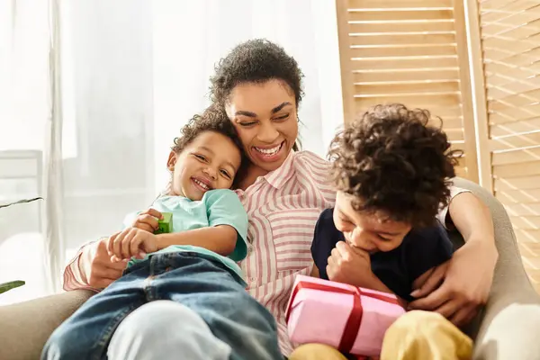 Joyeux afro-américain famille de trois passer du temps ensemble à la maison, présent dans la main, Fête des mères — Photo de stock