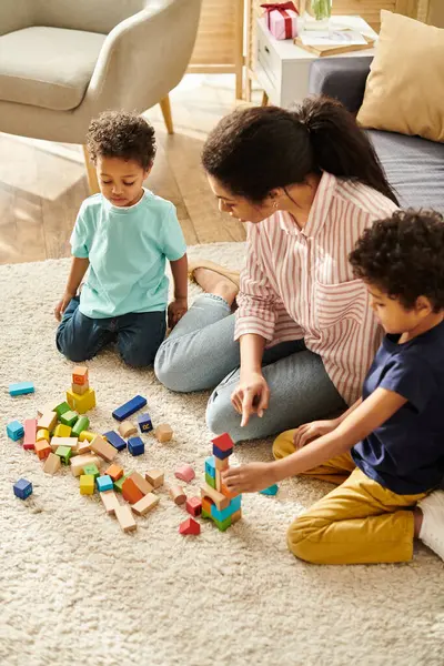 Atrativa afro-americana mãe brincando com brinquedos com seus adoráveis filhinhos em casa — Fotografia de Stock