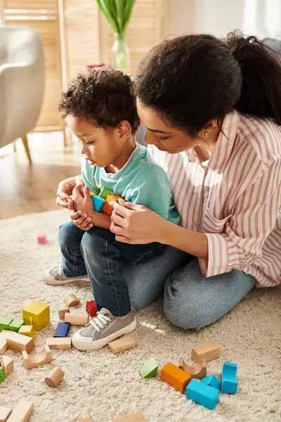 Good looking african american mother playing actively with her little cute son while in living room — Stock Photo