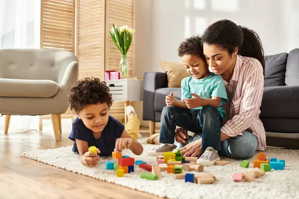 Fröhlich schöne afrikanisch-amerikanische Frau spielt mit Spielzeug mit ihren entzückenden kleinen Söhnen zu Hause — Stockfoto