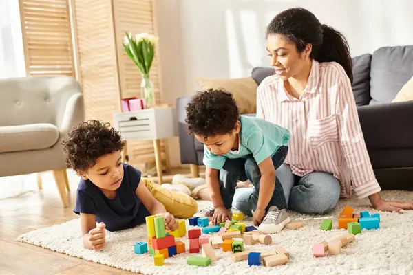 Alegre bela mãe afro-americana jogando ativamente com seus filhinhos bonitos em casa — Fotografia de Stock