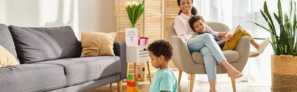 Niño afroamericano jugando con juguetes con su madre y su hermano en el fondo, pancarta - foto de stock