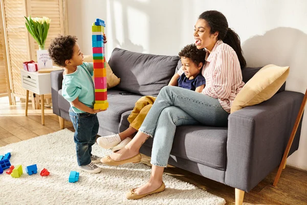 Alegre africano americano madre pasando tiempo con su alegre adorable hijos y jugando activamente - foto de stock