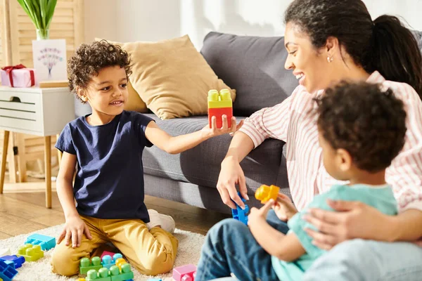 Freudige afrikanisch-amerikanische Mutter in kuscheliger Homewear, die viel Spaß mit ihren kleinen Söhnen zu Hause hat — Stockfoto