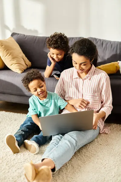 Cheerful african american woman in cozy attire watching movies with her adorable sons at home — Stock Photo