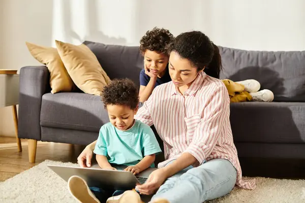 Bella donna afro-americana in homewear guardando film sul computer portatile con i suoi due figli jolly — Foto stock