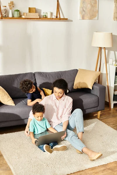Cheerful african american mother having fun with her little sons in front of laptop at home — Stock Photo