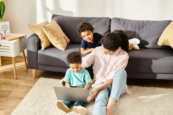 Alegre afroamericana madre en casa viendo películas con sus adorables hijitos en casa - foto de stock