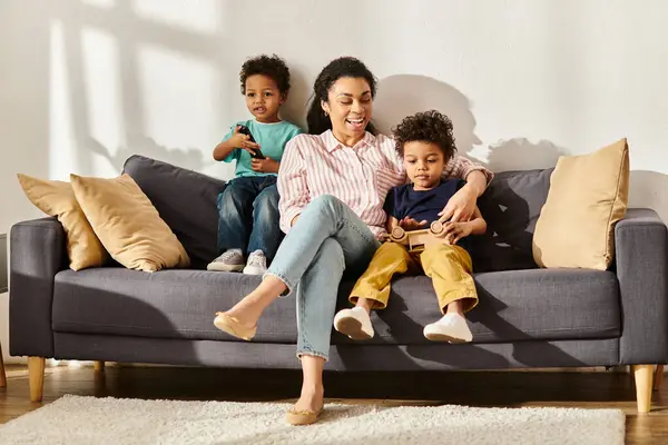 Allegra madre afro-americana in abbigliamento accogliente guardare film con i suoi adorabili piccoli figli — Foto stock