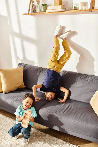 Alegre bonito afro-americano irmãos em confortável homewear se divertindo juntos na sala de estar no sofá — Fotografia de Stock