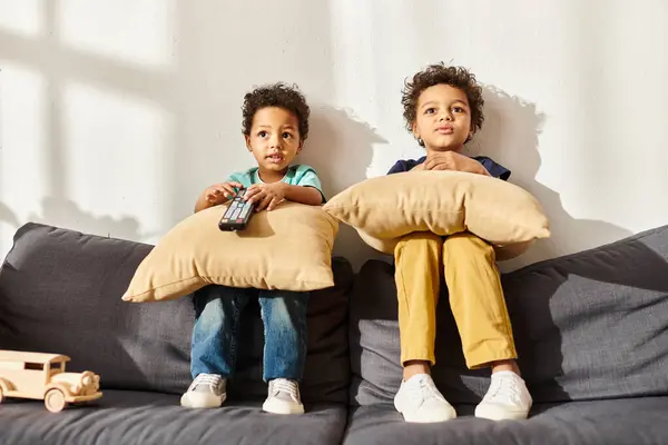 Adoráveis irmãos afro-americanos tendo grande tempo juntos brincando com carro de brinquedo de madeira no sofá — Fotografia de Stock