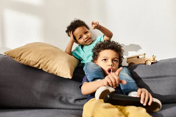 Choqué et joyeux frères afro-américains regarder la télévision tout en étant assis sur le canapé dans le salon — Photo de stock