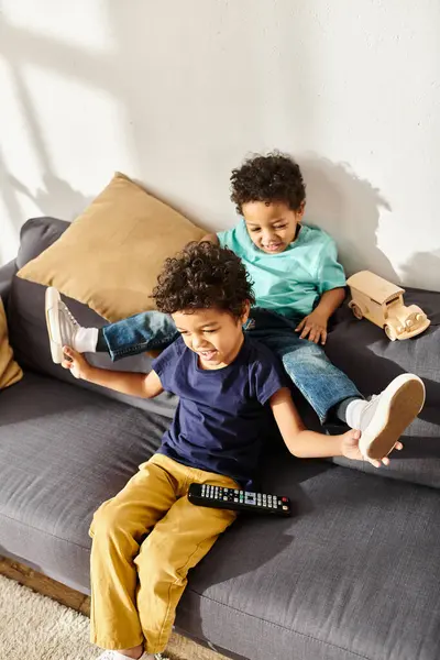 Alegres irmãos adoráveis em casa se divertindo enquanto se senta na frente da TV na sala de estar — Fotografia de Stock