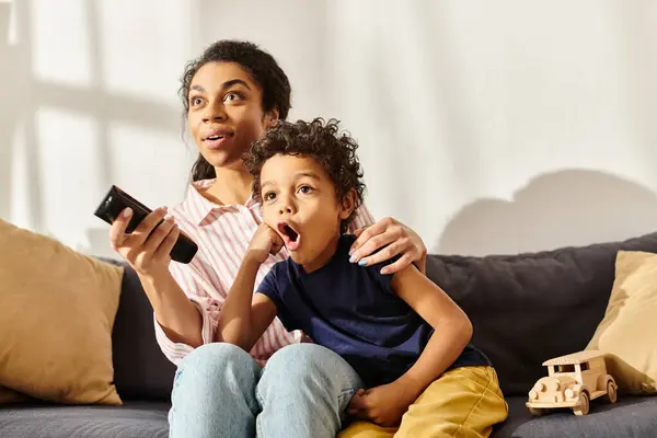 Sorpreso afroamericano madre e figlio seduto sul divano e guardare film, genitorialità moderna — Foto stock