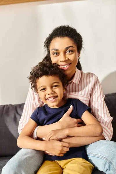 Alegre afroamericano madre e hijo en la ropa de casa abrazo y mirando a la cámara, crianza moderna - foto de stock