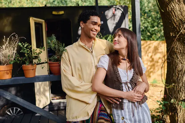 An interracial couple standing together in a natural setting, enjoying a romantic getaway in a camper van. — Stock Photo