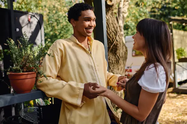 An interracial couple standing side by side in front of a camper van, enjoying a romantic getaway in a serene natural environment. — Stock Photo