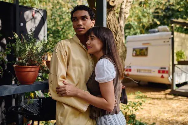 A man and woman of different races standing side by side, embracing, in a serene natural setting on a romantic getaway. — Stock Photo