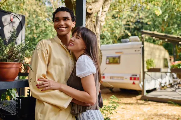 A man and a woman embrace warmly in front of a camper van, enjoying a romantic getaway in a natural setting. — Stock Photo