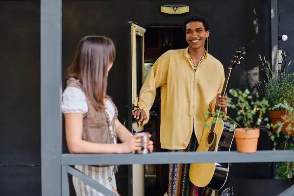 Uma mulher está ao lado de um homem com uma guitarra ao ar livre. — Fotografia de Stock