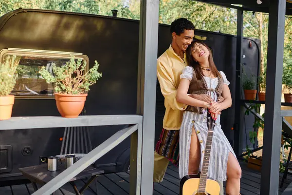 A man and woman, he holding a guitar, stand together in a natural setting, sharing a musical moment. — Stock Photo