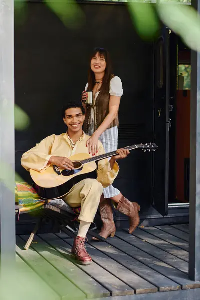 A man and woman sit on a porch playing guitar together, enjoying a moment of musical connection in a serene outdoor setting. — Stock Photo