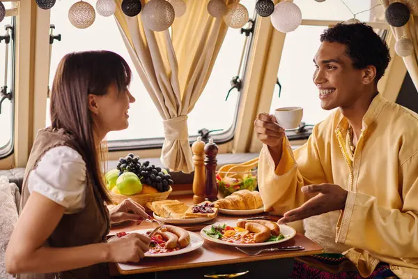 An interracial couple enjoying a delicious lunch in their camper van. — Stock Photo