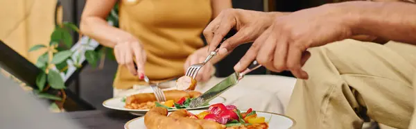 An interracial couple joyfully cutting into a plate of food together in a camper van on a romantic getaway. — Stock Photo