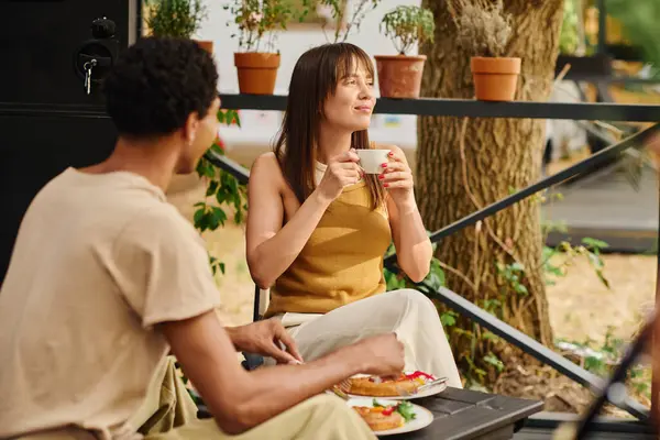 Un homme et une femme profitent d'un moment paisible sur un banc, savourant des tasses de café en compagnie les uns des autres. — Photo de stock