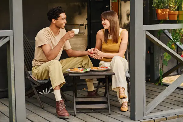 A man and a woman sit on a porch, enjoying a delicious meal together. — Stock Photo