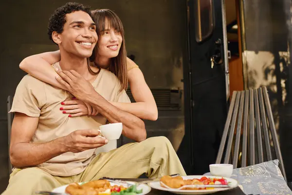 A man and woman, an interracial couple, sitting on a bench, enjoying each others company in a peaceful setting. — Stock Photo