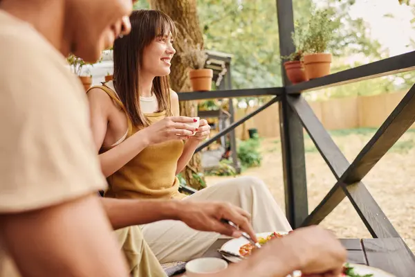 Una coppia interrazziale gode di un momento di pace su una panchina, condividendo un pasto insieme in un ambiente parco panoramico. — Foto stock