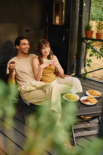 Una coppia interrazziale si siede insieme su un accogliente portico, godendo di un tranquillo momento di relax. — Foto stock