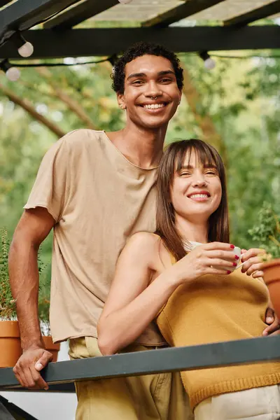 A man and a woman stand side by side, taking in the scenery before them while on a romantic getaway in a camper van. — Stock Photo