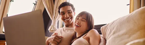 A man and woman sit on a couch, engrossed in a laptop screen, sharing a moment of connection and discovery. — Stock Photo