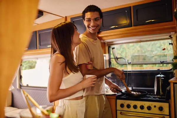 Um casal inter-racial cozinhar juntos dentro de uma van campista em uma escapadela romântica, cercado por vibrações acolhedoras. — Fotografia de Stock