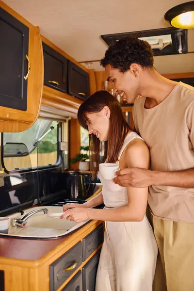 A man and woman, of different races, standing together in a kitchen beside a sink. — Stock Photo