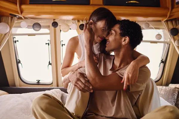 Un homme et une femme de races différentes assis sur un lit, partageant un moment d'intimité et de connexion ensemble. — Photo de stock